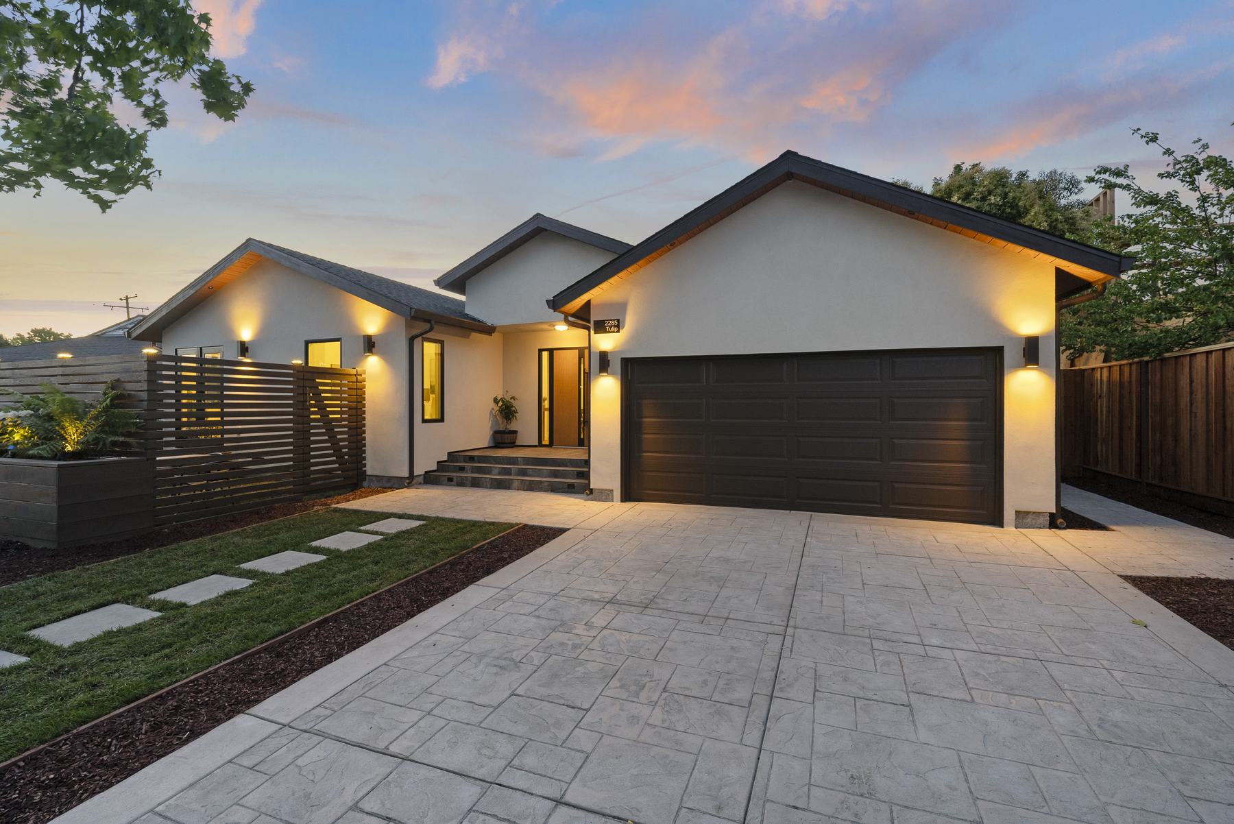 Front exterior at twilight with new stucco, roofline, and driveway