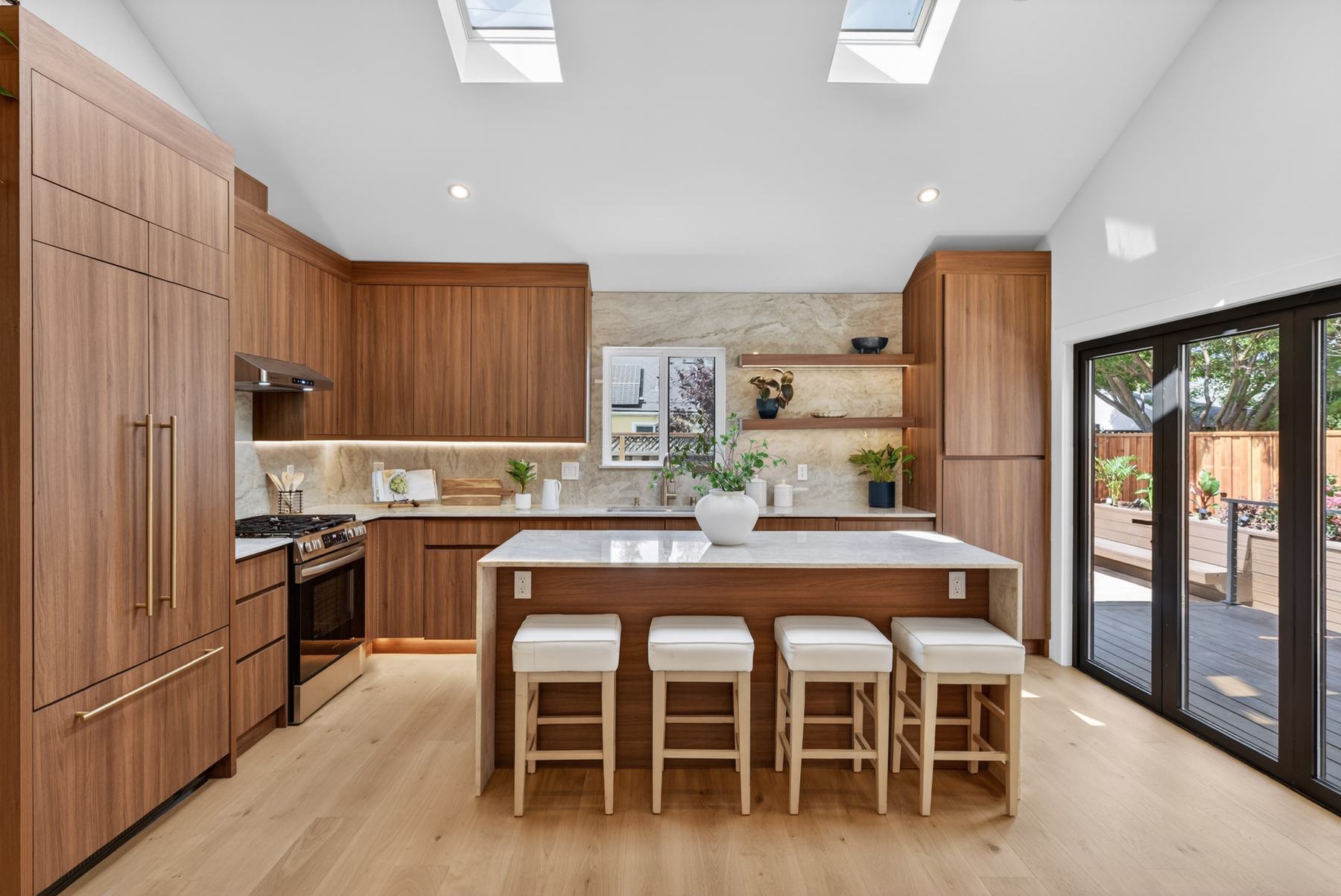 Renovated kitchen with walnut cabinetry, stone backsplash, and skylights