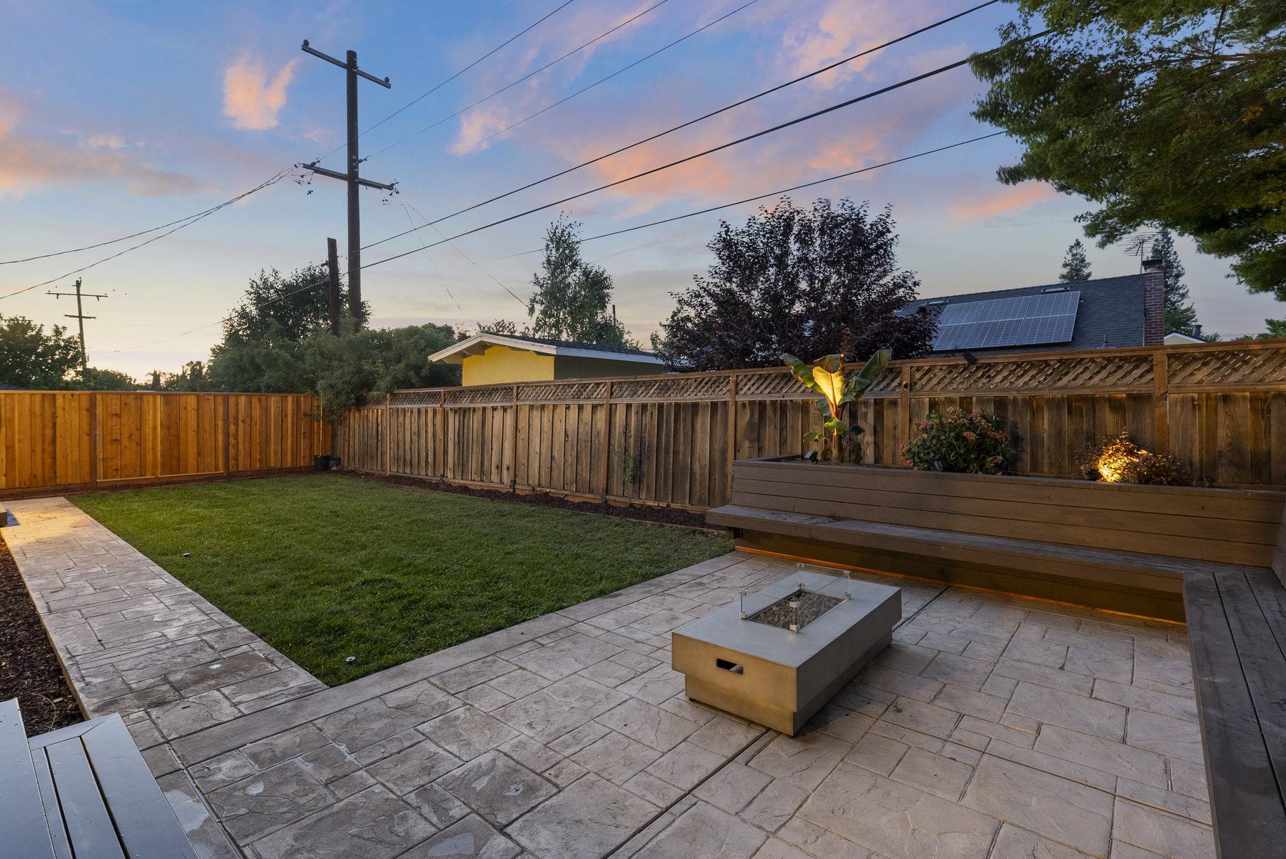Backyard with stamped concrete patio, lawn, fire feature, and built-in bench