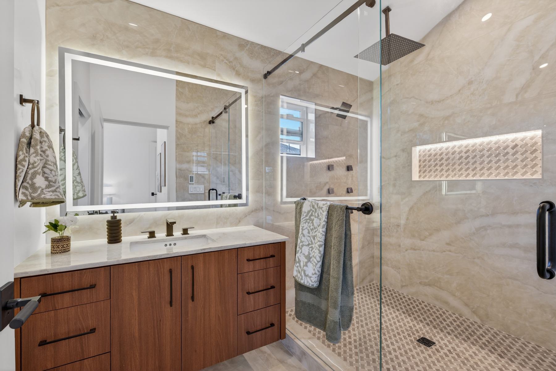 Primary bathroom with large-format stone tile and glass shower